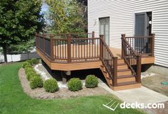 a wooden deck with railings next to a house