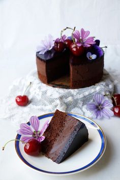 a piece of chocolate cake on a plate with cherries