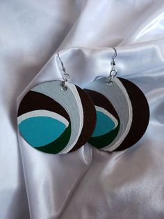 two circular wooden earrings on a white satin background with silver earwires and hooks