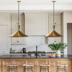 a kitchen with three pendant lights hanging over the island