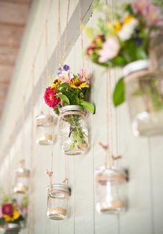 mason jars filled with flowers hanging from strings