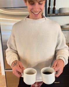 a man holding two cups of coffee in his hands