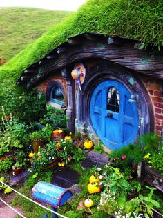 a hobbot house with blue door surrounded by plants and flowers