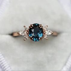 an engagement ring with a blue and white diamond in the center, on top of a piece of cloth