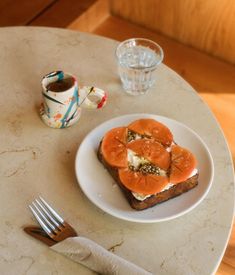 a white plate topped with slices of toast next to a cup of tea and a fork