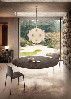 a modern dining room with stone walls and large glass doors leading to an outdoor garden