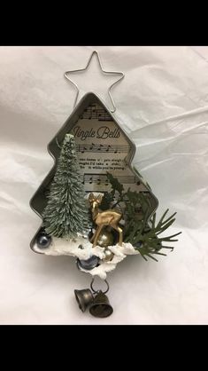 a metal christmas tree decoration with bells and trees in it on a white sheeted background