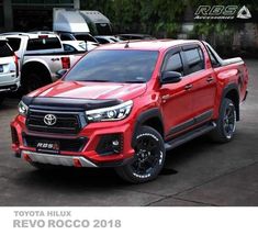 a red toyota hilux is parked in front of other cars