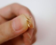 a hand holding a tiny gold heart ring