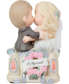 a figurine of a bride and groom kissing on the back of a car