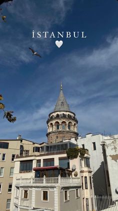 an old building with a bird flying in the sky above it and some buildings behind it