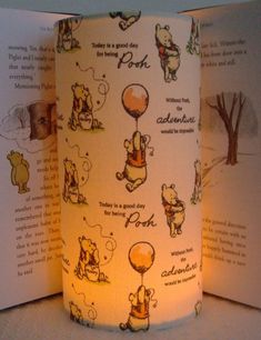 an open book with winnie the pooh drawings on it and some lights in front of it