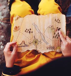 a person sitting on the ground looking at a piece of paper that has been embroidered onto it