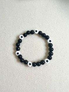 a black and white beaded bracelet with stars on the beads is sitting on a table