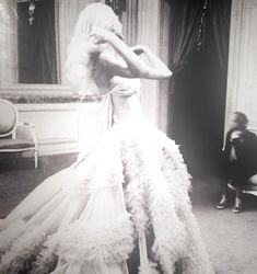 a black and white photo of a woman in a wedding dress with feathers on it