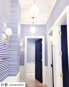 a hallway with blue and white striped wallpaper, wood flooring and gold trim