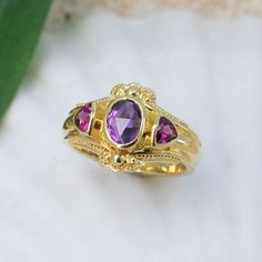 Adorn yourself with this stunning, 18K granulated golden ring showcasing a majestic combination of beautiful amethyst and vibrant rhodolite garnets. Add a regal touch to any occasion and feel like a queen. 18KY granulated ring with 7x5mm uniquely-cut amethyst and 2- 4mm rhodolite garnets. The granulation on runs part way down the band resulting in a band width of 4.7mm. Currently size 6.75, but each ring comes with free sizing and FREE SHIPPING! Unsure what ring size you are? It's always best to Golden Ring, Special Ring, Way Down, Rhodolite Garnet, Garnet, Jewelry Collection, Amethyst, Queen, Engagement Rings