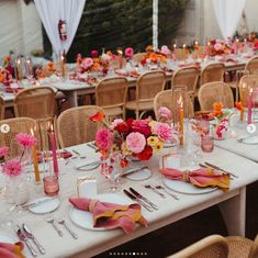 the tables are set with pink and orange flowers in vases, silverware, and napkins