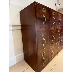 a large wooden cabinet with brass handles and drawers on the front, in a room with white walls