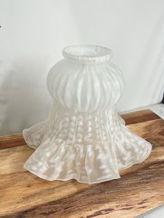 a white vase sitting on top of a wooden table