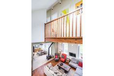 a living room filled with furniture next to a wooden bannister above a fire place