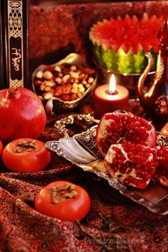 an assortment of fruits and vegetables on a table with candles in front of the food