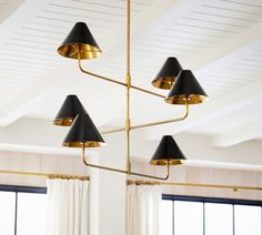 a chandelier hanging from the ceiling in a room with white curtains and windows