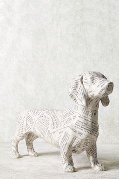 a dog made out of books sitting on top of a white floor next to a wall