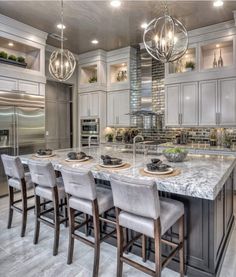 a large kitchen with an island and marble counter tops in front of stainless steel appliances