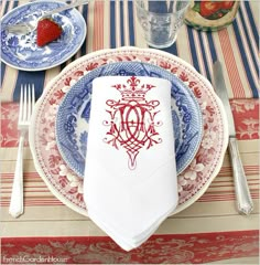 a place setting with red and blue plates, silverware, and strawberries on the table