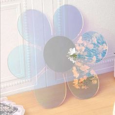 a vase filled with flowers sitting on top of a wooden floor next to a wall