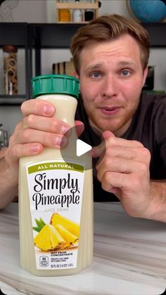 a man holding a bottle of simply pineapple juice