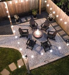 an outdoor fire pit surrounded by chairs and lights