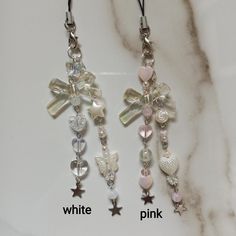 two earrings with charms attached to them on a marble surface