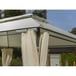 an outdoor covered patio with curtains on the side and trees in the backgroud