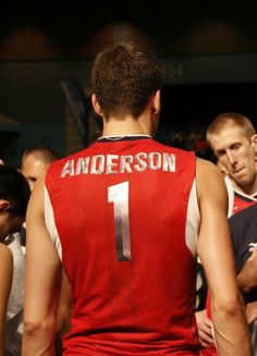 a group of men standing next to each other in front of a basketball ball court