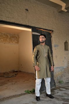 A unique dhani-colored silk kurta and plain cotton silk pajama with gold embroidery and motifs on the placket. Model wears Small/Medium. Gold Lawn Suit With Naqshi In Traditional Drape, Gold Raw Silk Lawn Suit For Festivals, Gold Straight Kurta Lawn Suit In Raw Silk, Gold Raw Silk Lawn Suit With Straight Kurta, Gold Chanderi Lawn Suit With Dabka Detailing, Designer Gold Lawn Suit With Naqshi, Gold Jamawar Lawn Suit For Festivals, Gold Unstitched Jamawar Kurta, Gold Chanderi Sherwani With Dabka Work