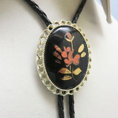 This lovely antique porcelain  bolo is made from a hand painted  cabochon.  It is a  floral scene on black porcelain.  It is very striking.   The bolo slide measures 2  inches tall and 1 5/8th inches wide. It is placed on a new 36 inch long braided black leatherette string tie with bright golden brass end caps. This fellow will arrive in a lovely gift box for easy gift giving.. If you like vintage bolo ties, western accessories, vintage Mexican and Native American silver and vintage jewelry, kin Vintage Black Bolo Ties For Gift, Vintage Black Bolo Ties As Gift, Artistic Black Collectible Jewelry, Vintage Black Hand-painted Jewelry, Vintage Black Hand Painted Jewelry, Mexican Accessories, Black Porcelain, Western Accessories, Bolo Ties