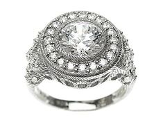 a white gold ring with an oval cut diamond surrounded by smaller round diamonds and leaves