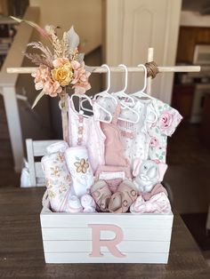 a baby's gift box with clothes and flowers on it, sitting on a table