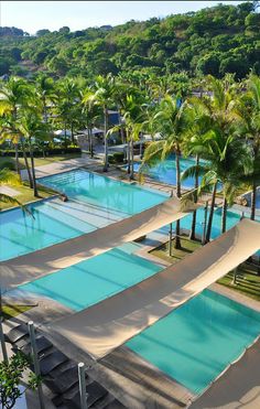 an aerial view of a resort pool surrounded by palm trees