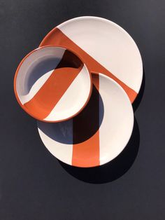 two orange and white plates sitting next to each other on top of a black surface