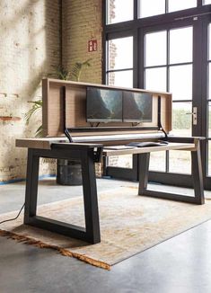 a desk with a tv on top of it in front of a window and a rug