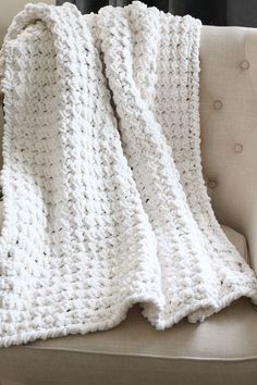 a white crocheted blanket sitting on top of a couch