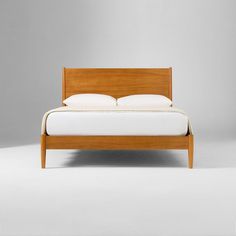 a bed with white sheets and wooden headboard on top of it, against a gray background