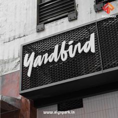 a sign that reads yardbird hanging from the side of a white brick building in front of a window