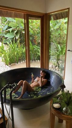 a woman sitting in a large bathtub next to a table with flowers on it