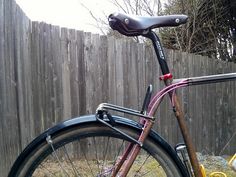 a pink bicycle parked next to a wooden fence