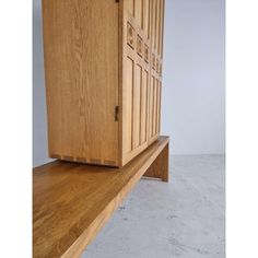 a wooden cabinet sitting on top of a white floor next to a shelf with drawers