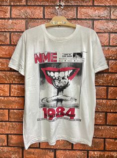 Vintage 90s NME British Music Magazine 1984 Cover Shirt / Britpop / Alternative Music / English Rock Band Size M Condition : Good Used  Size on tag : M Colour : White Brand : Unknown Measurement : Armpit to armpit - 20.5" Length - 26" Material : Cotton Made In: Unknown THE SHIPPING (Your Choice Please read) 1. The shipping cost is USD 20 via Malaysian Registered Postage With Tracking Number. It will take 2-4 weeks or more for delivery, depends on your custom checking. 2. Add USD 10 for speedy de Dark Spirit, British Music, Music Magazine, Music Magazines, Punk Bands, Alternative Music, Band Merch, Selling Clothes, White Brand